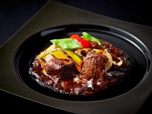 a black plate of food with meat and vegetables at APA Hotel & Resort Osaka Namba Ekimae Tower in Osaka
