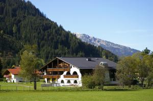 ein großes weißes Gebäude vor einem Berg in der Unterkunft Landhaus Schnöller in Tannheim