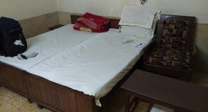 KedārnāthにあるMuktinath Guest Houseの白いシーツが敷かれたベッドとバックパック