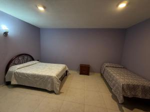 a bedroom with two beds in a room with purple walls at Villa los Encinos  +8 photos