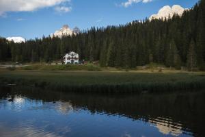 a house on the shore of a lake with mountains at Hotel Miralago in Misurina