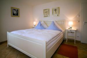 a white bed with blue pillows in a bedroom at Ferienwohnungen Birkenhof in Bad Wörishofen