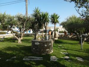 a garden with palm trees and a stone fountain at Pension Sofia in Parikia