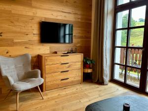 a room with a chair and a television on a wall at Apartmány Kvilda & Srní in Kvilda