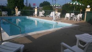 - une piscine avec des chaises blanches, des tables et des chaises dans l'établissement Baymont by Wyndham Cave City, à Cave City