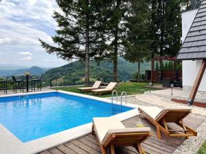 a swimming pool with two chairs and a table at Mountain House LISINSKA ROSA in Brdo