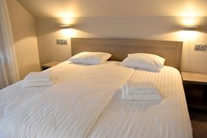 a large white bed with two pillows on it at Kuršu krogs in Dižstende