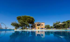 a swimming pool with chairs and a house in the background at Mediterraneo Luxury Suites Halkidiki in Vourvourou