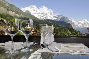 a table with wine glasses on a table with a view at Hotel Maya Caprice in Wengen