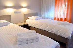 2 bedden in een hotelkamer met witte lakens bij Kuršu krogs in Dižstende