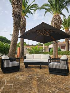 a couch and an umbrella in front of palm trees at Le Palme B&B in Salemi