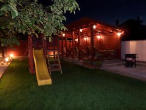 un parque infantil con un tobogán en un patio por la noche en Oregano Apartman By BLTN, en Siófok
