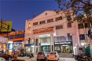 un edificio rosa con coches estacionados frente a él en Hotel Ashish Palace en Agra