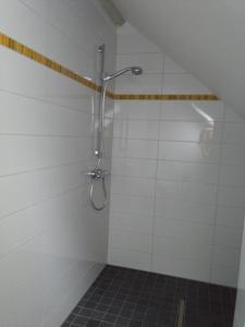 um chuveiro na casa de banho com azulejos brancos em De Ploeg em Manderfeld