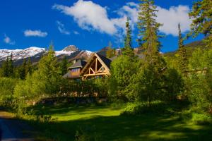 a log home in the mountains with a green yard at Vagabond Lodge at Kicking Horse in Golden