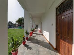 an empty hallway with potted plants and a wooden door at Super Hotel O Madhuraj Palace Takrohi Road in Chinhat