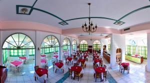 a dining room with red chairs and tables and windows at Arion Hotel in Kokkari