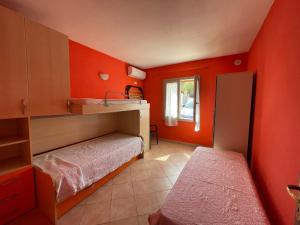 1 dormitorio con paredes de color naranja, 1 cama y ventana en Casa Rosanna, en Lu Lioni