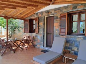 a patio with a table and chairs and a stone wall at Pelagos Villas in Agios Dimitrios