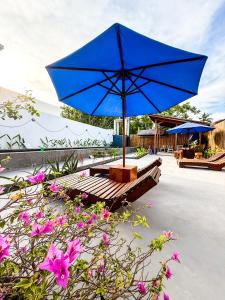 un ombrello blu appoggiato su una panchina con dei fiori di Hotel Gili Trawangan & Dive a Gili Trawangan