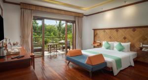 a bedroom with a bed and a desk and a balcony at Khmer House Resort in Siem Reap +37 photos