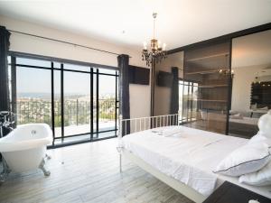 Un dormitorio con una cama grande blanca, una bañera y un lavabo. en לה פטלונה - ווילה מהממת עם בריכה פרטית מחוממת ומקורה בכפר ורדים, en Kefar Weradim