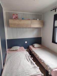 twee bedden in een kleine kamer met ermottermottermott bij Mobil home 2 chambres camping 4 étoiles vias in Vias