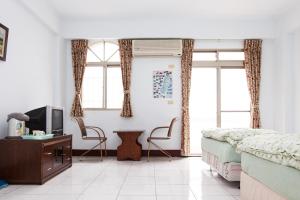 a bedroom with a bed and a tv and two chairs at 峽谷民宿 Valley B&B in Fushi