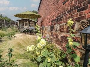 eine Backsteinwand mit einem Tisch und einem Regenschirm in der Unterkunft Red Grouse Cottage in Guisborough