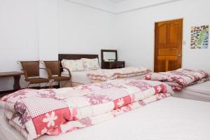 una camera con tre letti con coperte rosa e bianche di 峽谷民宿 Valley B&B a Fushi