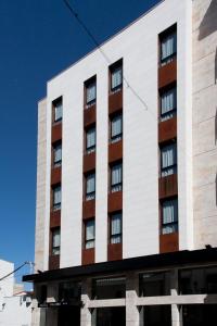 un edificio alto de color blanco con ventanas en Hotel Paloma en Tomelloso