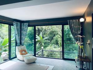a living room with a white chair and large windows at Brookside Nest- Lower Floor in Ban Huai Kaeo +5 photos