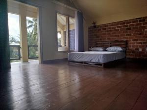 a bedroom with a bed and a brick wall at ARISTA Homestay in Tetebatu