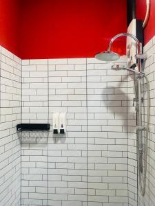 a shower in a bathroom with a red wall at The 10 club hostel in Thongsala