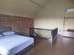 a room with a bed and a brick wall at ARISTA Homestay in Tetebatu