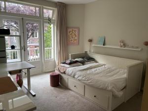 a bedroom with a bed and a desk and windows at 185m2 groot appartement met tuin in City Centre in Amsterdam