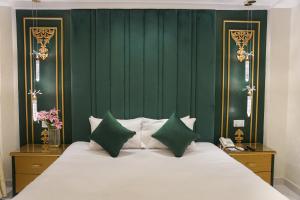 a bedroom with a bed with a green wall at Dimora Hotel Anarkali in Lahore