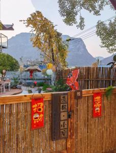 ein Zaun mit Schildern daran und einem Berg im Hintergrund in der Unterkunft Guilin Tranquil Peaks Retreat by Reed Flute Cave in Guilin