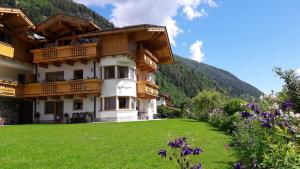 a large building with a green lawn in front of a mountain at Landhaus Alpensonne in Neustift im Stubaital