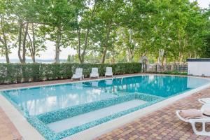 a swimming pool with chairs and trees in a yard at Hotel Anna Villa in Balatonföldvár