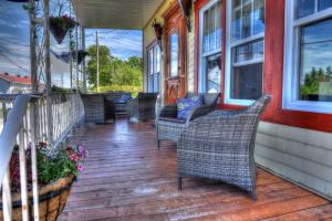 a porch with wicker chairs and tables on a house at Gîte Grand-Père Nicole in Val-Brillant