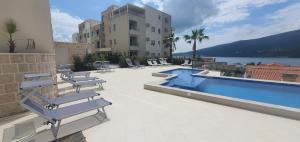 a swimming pool with lounge chairs next to a building at Bella Vista Pleasure in Baošići
