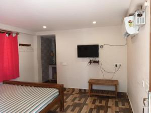 a bedroom with a bed and a tv on the wall at Ranga Cottages in Kuilapayam