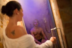 a woman taking a picture of a man in a mirror at PALAZZO DEL CAPITANO Wellness & Relais - Luxury Borgo Capitano Collection in San Quirico dʼOrcia +253 photos