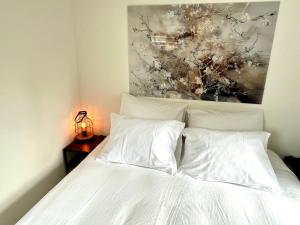 a bed with white sheets and a painting above it at Huisje Eext - De Vos in Eext