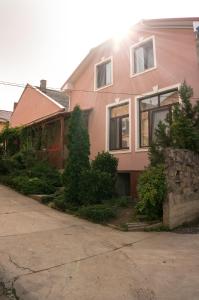 a pink house with trees in front of it at Кімнати в центрі in Uzhhorod