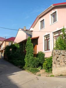 una casa rosa con un árbol delante en Кімнати в центрі, en Uzhhorod