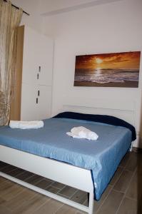 una camera da letto con un letto con lenzuola blu e un dipinto sul muro di Rose Beach Apartment a Margherita di Savoia