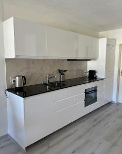 a kitchen with white cabinets and a sink at Family friendly duplex with free parking in Leukerbad