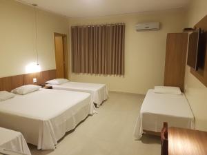 a hotel room with two beds and a television at Oft Place Hotel in Goiânia